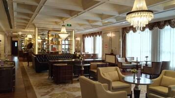 A hotel lobby with a bar area, seating arrangements, and a chandelier.