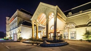 A hotel with a grand entrance, large columns, and a well-lit facade. - Old Tram Hotel (Tianjin)