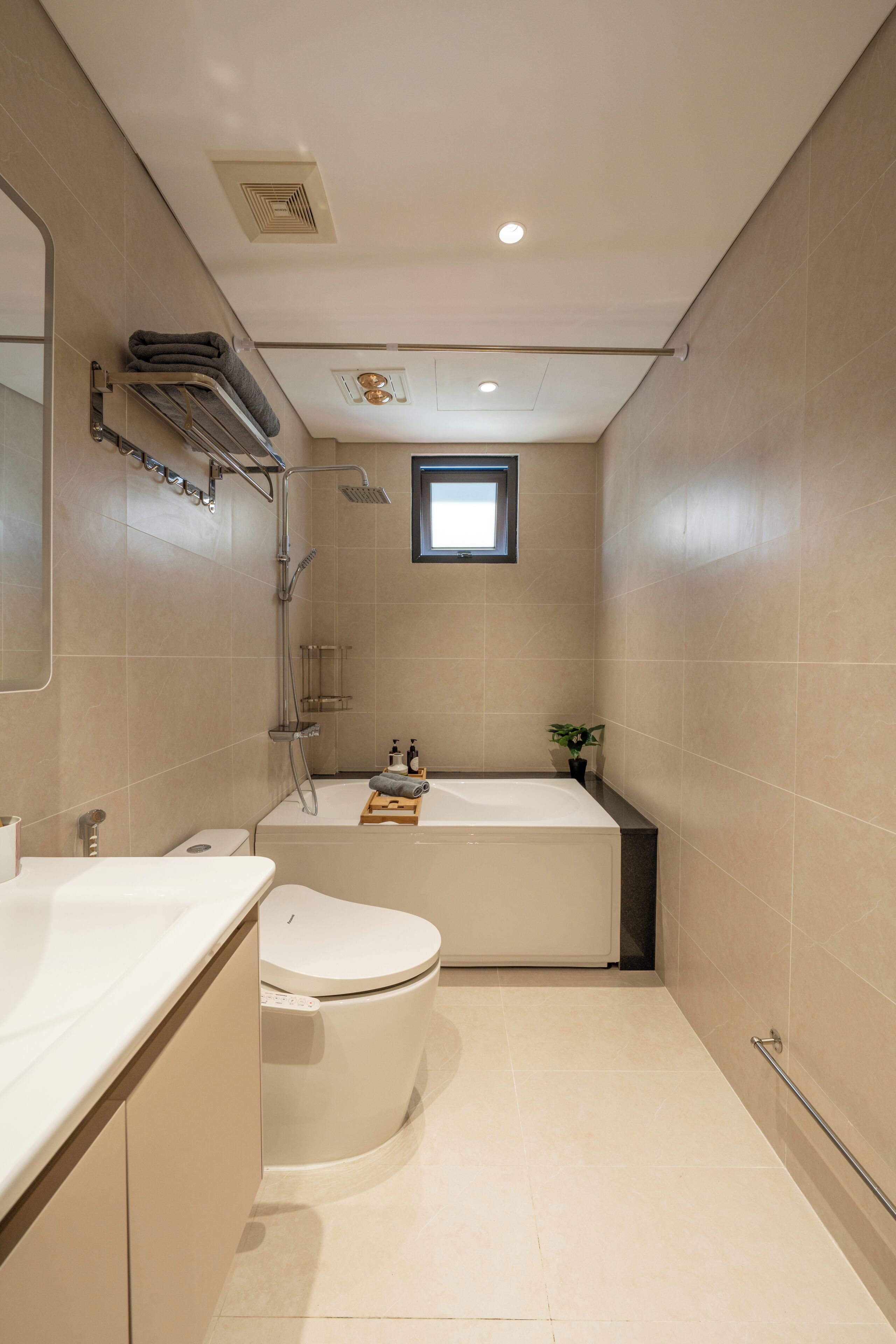 Ein kleines Badezimmer mit Toilette, Waschbecken, Dusche und Badewanne. Über der Badewanne befindet sich ein kleines Fenster und an der Wand ein Handtuchhalter.