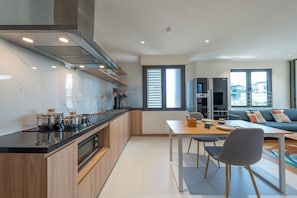 Une cuisine moderne avec un coin repas, un canapé et une fenêtre équipée de stores.