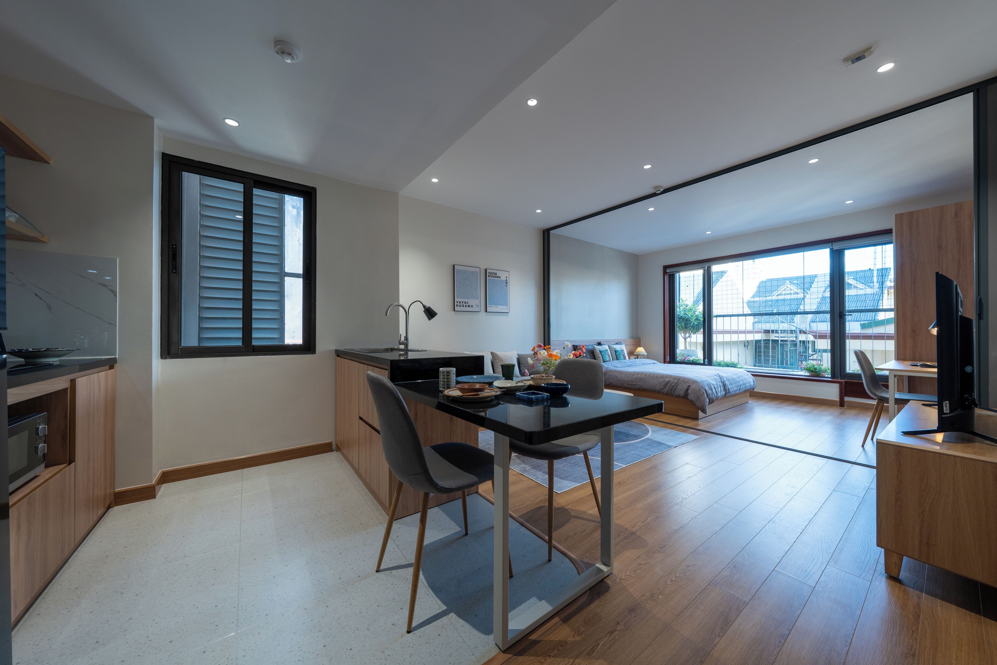 A modern apartment with a kitchen, dining area, and a bedroom with a large window.