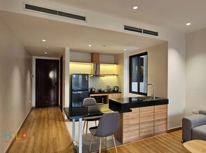 A modern kitchen with a black countertop, wooden cabinets, and a built-in stove. - HoLo Giang Vo Hanoi - Serviced HomeStay (Hanoi)
