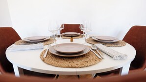 Una mesa redonda para comer con platos, cubiertos y vasos para cuatro personas.