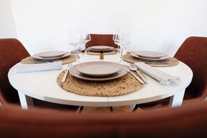 A round dining table with plates, cutlery, and glasses set for four. - Alma Residence Vibrant City Center Bucharest (București)