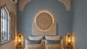 Un dormitorio con una cama grande, dos mesitas de noche con lámparas, un elemento decorativo sobre la cama y una ventana con vistas.