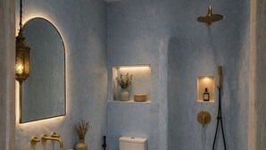 Un baño con lavamanos dorado, inodoro blanco y zona de ducha.