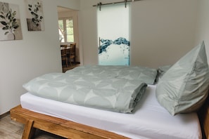 Ein Bett mit gemustertem Überwurf, einem Holzkopfende und einer Wand mit Wasserspritz-Kunstwerk.