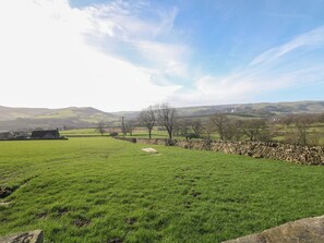 A rural landscape with a stone wall, open fields, and distant hills. - Thorn Tree Cottage (Hope Valley)