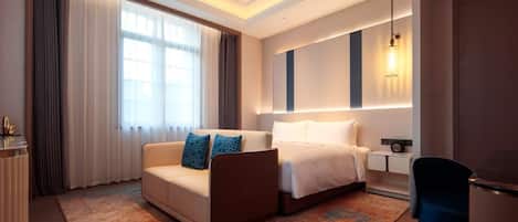 A hotel room with a bed, a sofa, a desk, and a chair.