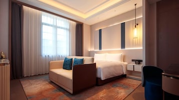 Una habitación de hotel con una cama, un sofá, un escritorio y una silla.