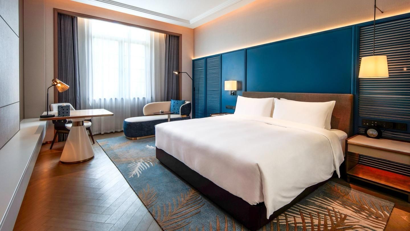 A hotel room with a large bed, a desk, a chair, and a television.