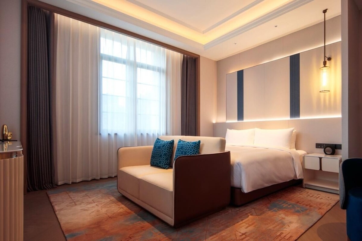 A hotel room with a bed, a sofa, a desk, and a chair.
