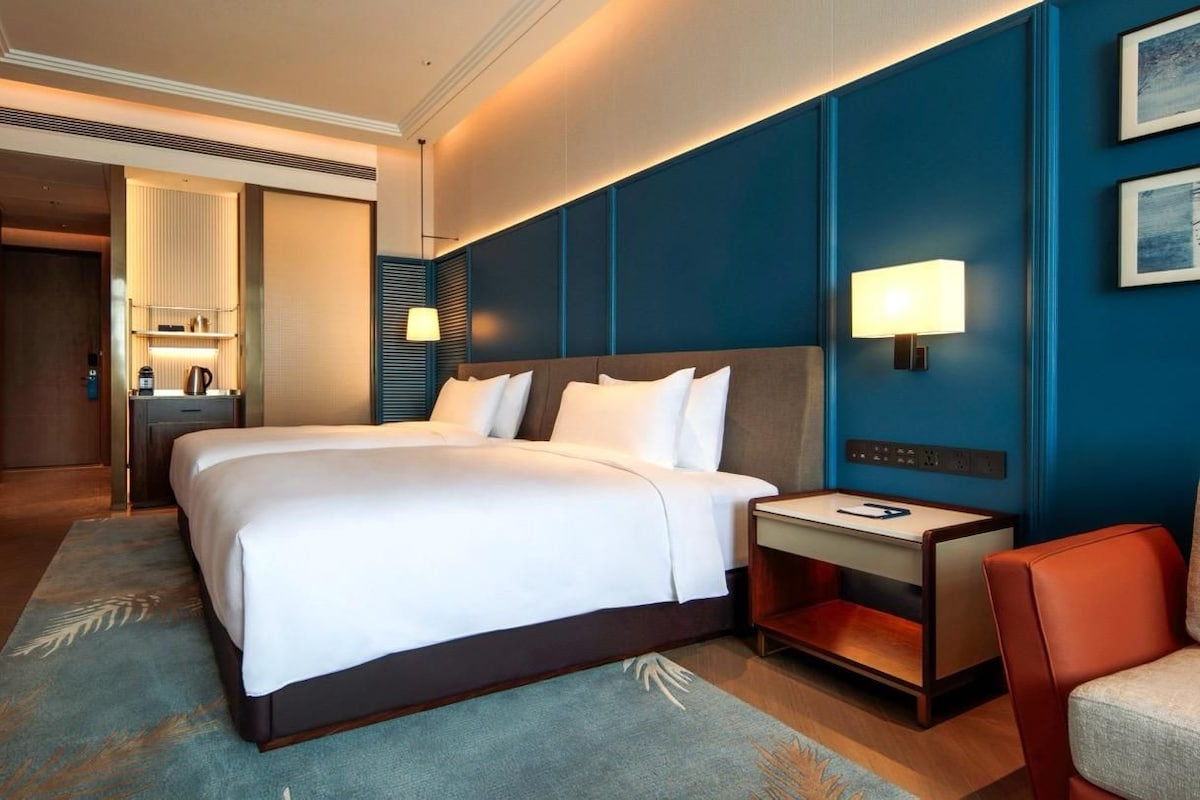 A hotel room with a large bed, bedside tables, a desk, and a chair.