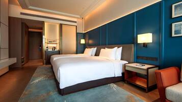 A hotel room with a large bed, bedside tables, a desk, and a chair.