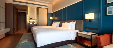 A hotel room with a large bed, bedside tables, a desk, and a chair.