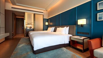 A hotel room with a large bed, bedside tables, a desk, and a chair.