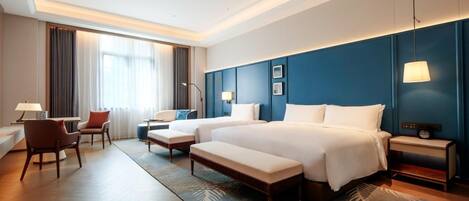 A hotel room with a large bed, a desk, a chair, and a lamp.