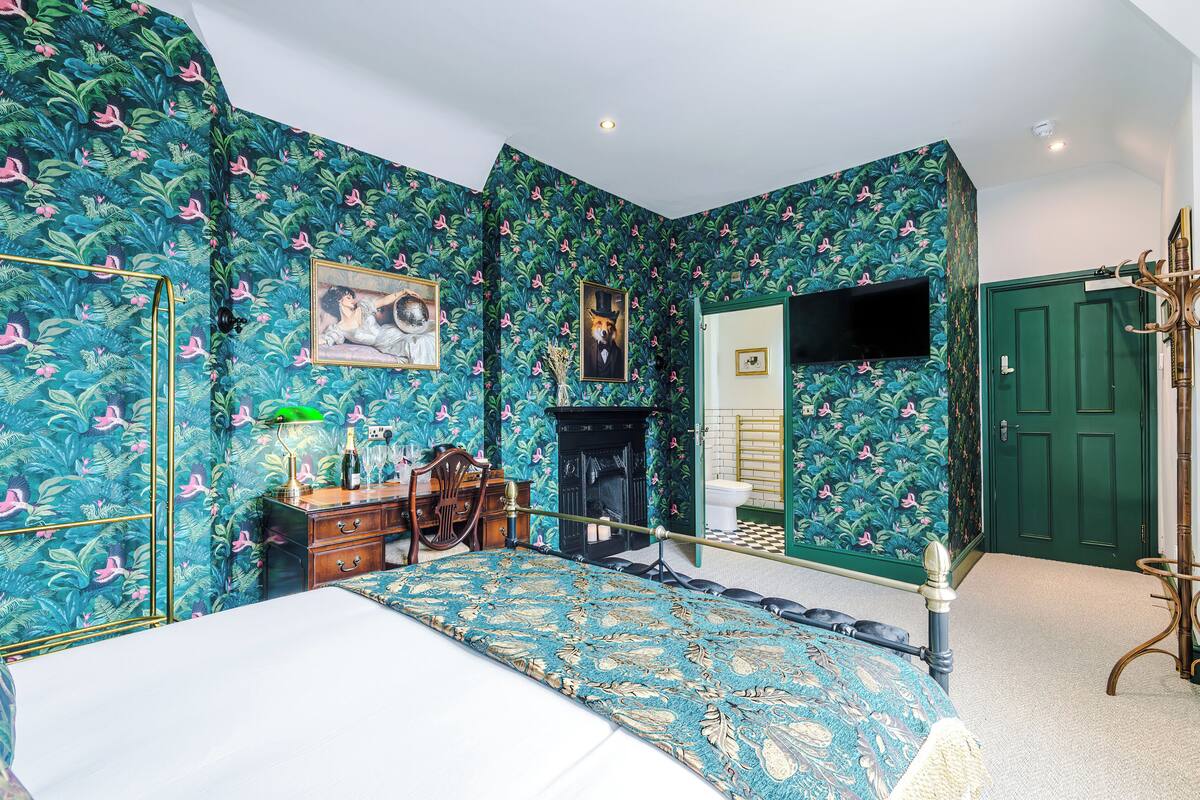 A bedroom with a bed, a dresser, a mirror, and a television.