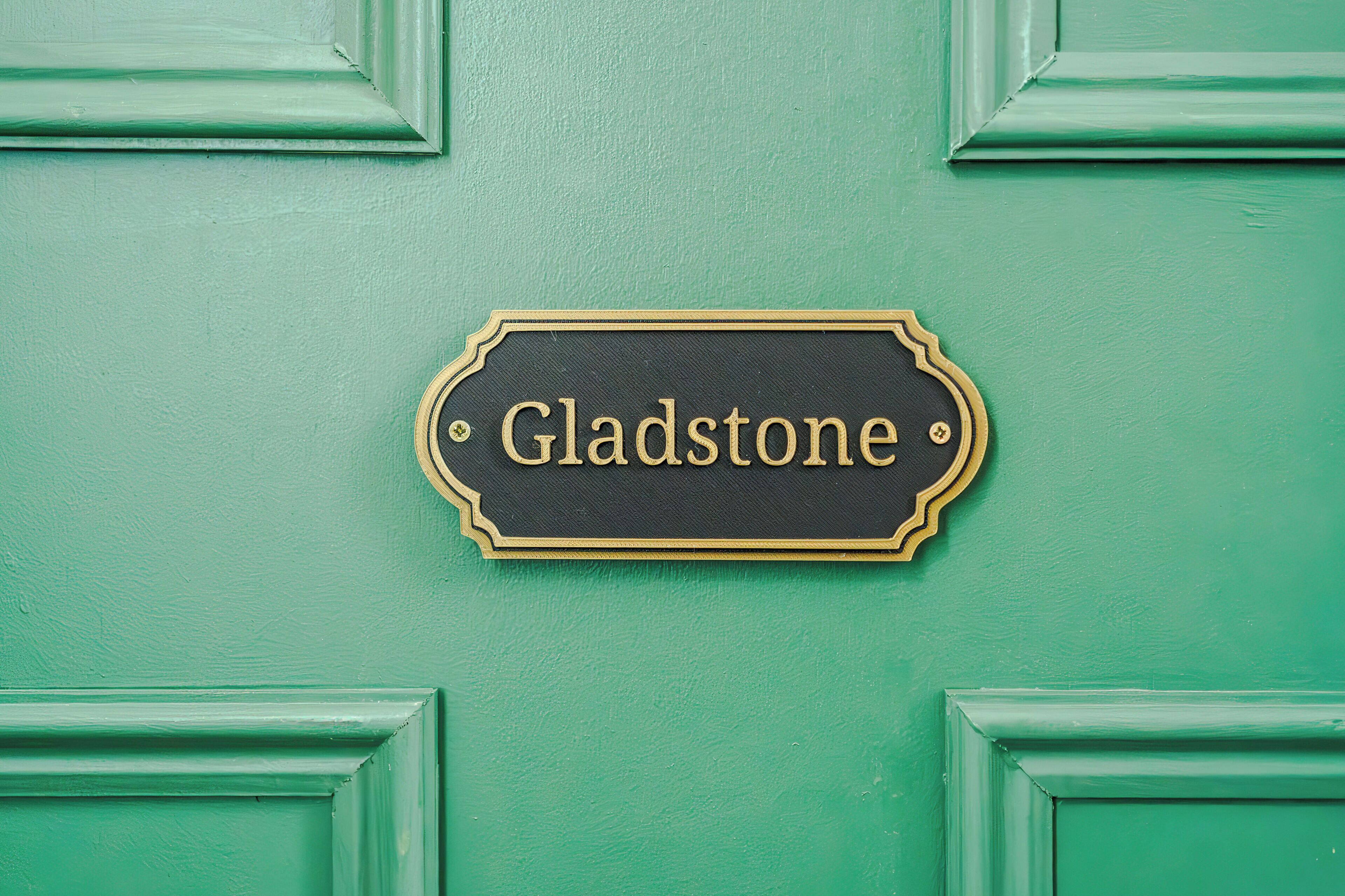 A sign with the name 'Gladstone' on a green door.