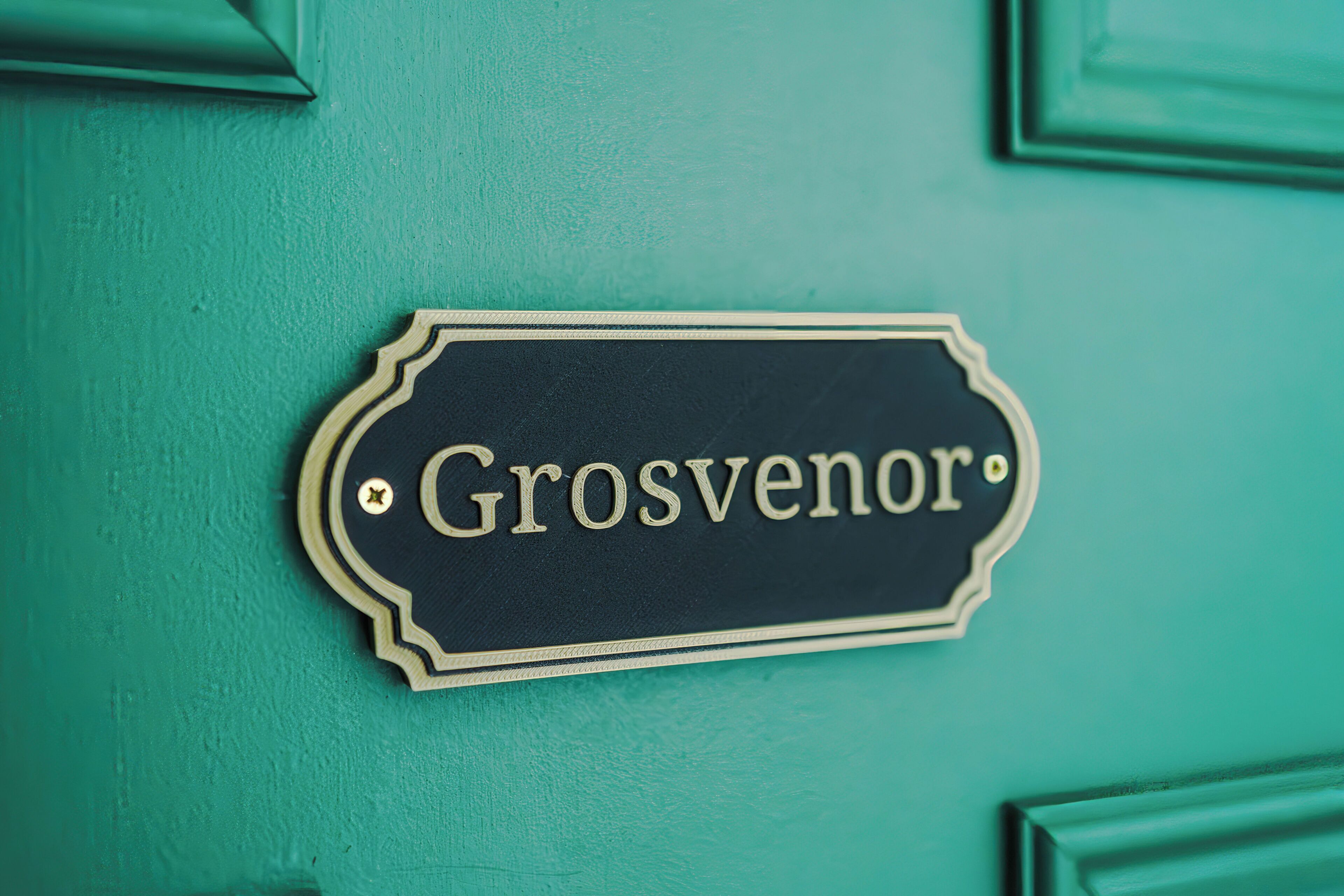 A sign with the name 'Grosvenor' on a teal door.