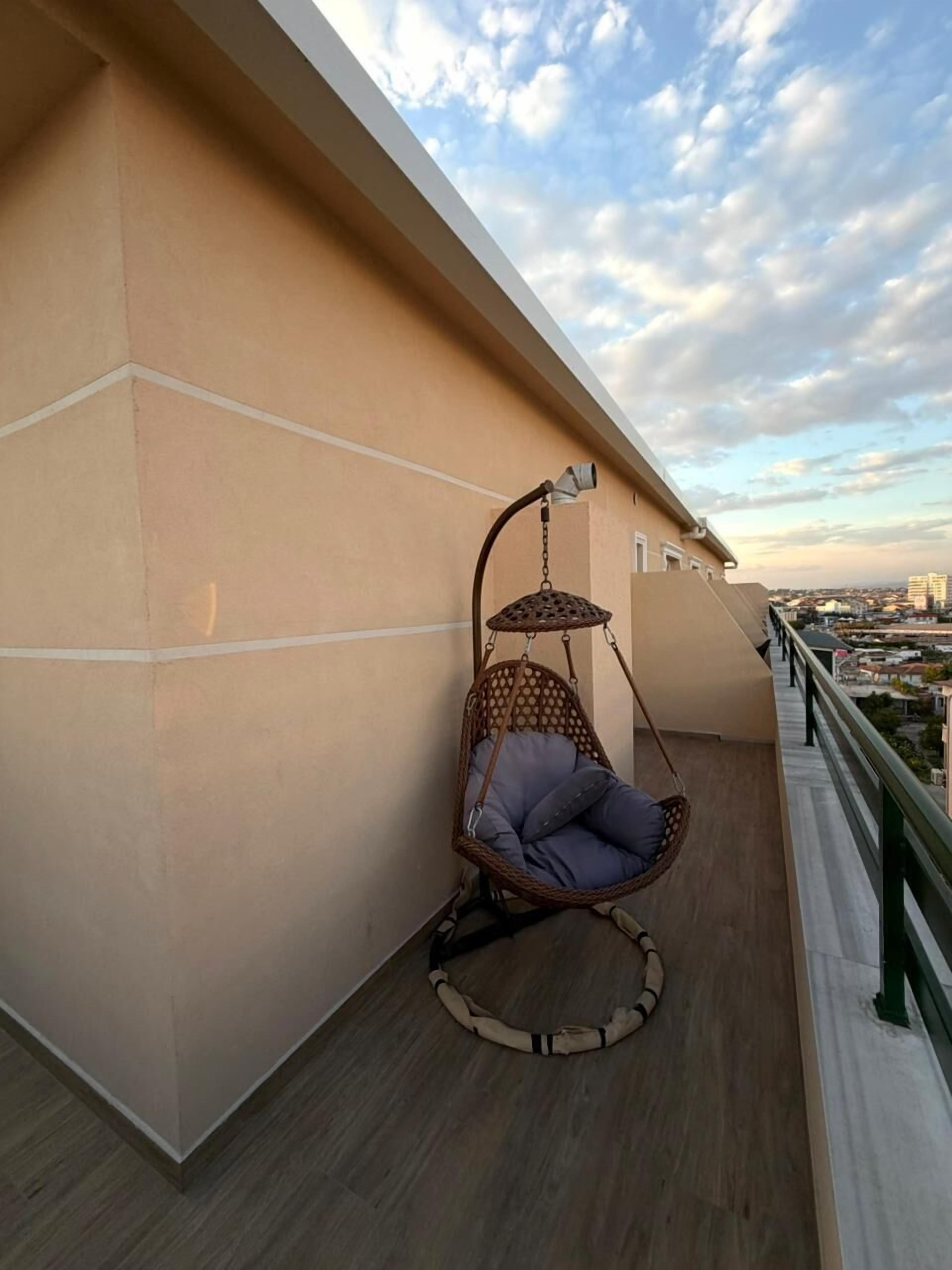 Un balcón con una hamaca colgante, baranda y vista a la ciudad.
