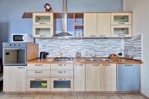 Eine Küche mit Holzausstattung, einer Mikrowelle, einem Backofen, einem Gasherd und einem Spülbecken.