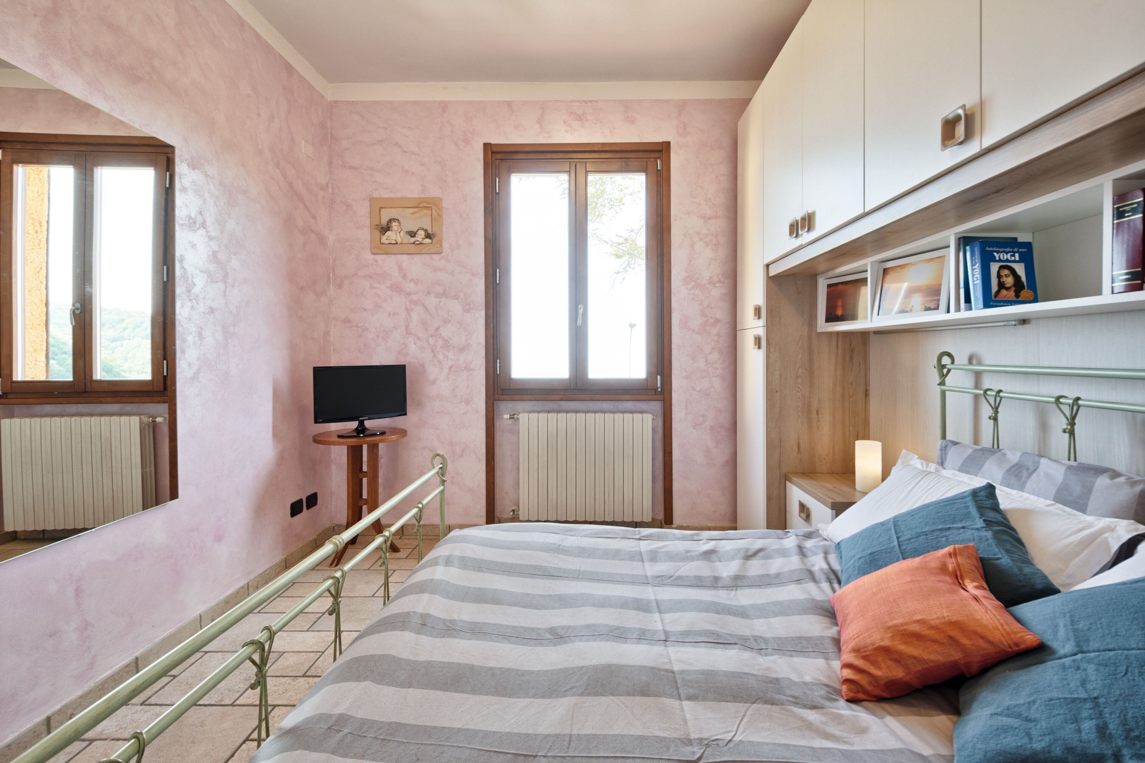 A bedroom with a bed, a television, a bookshelf, and a window.