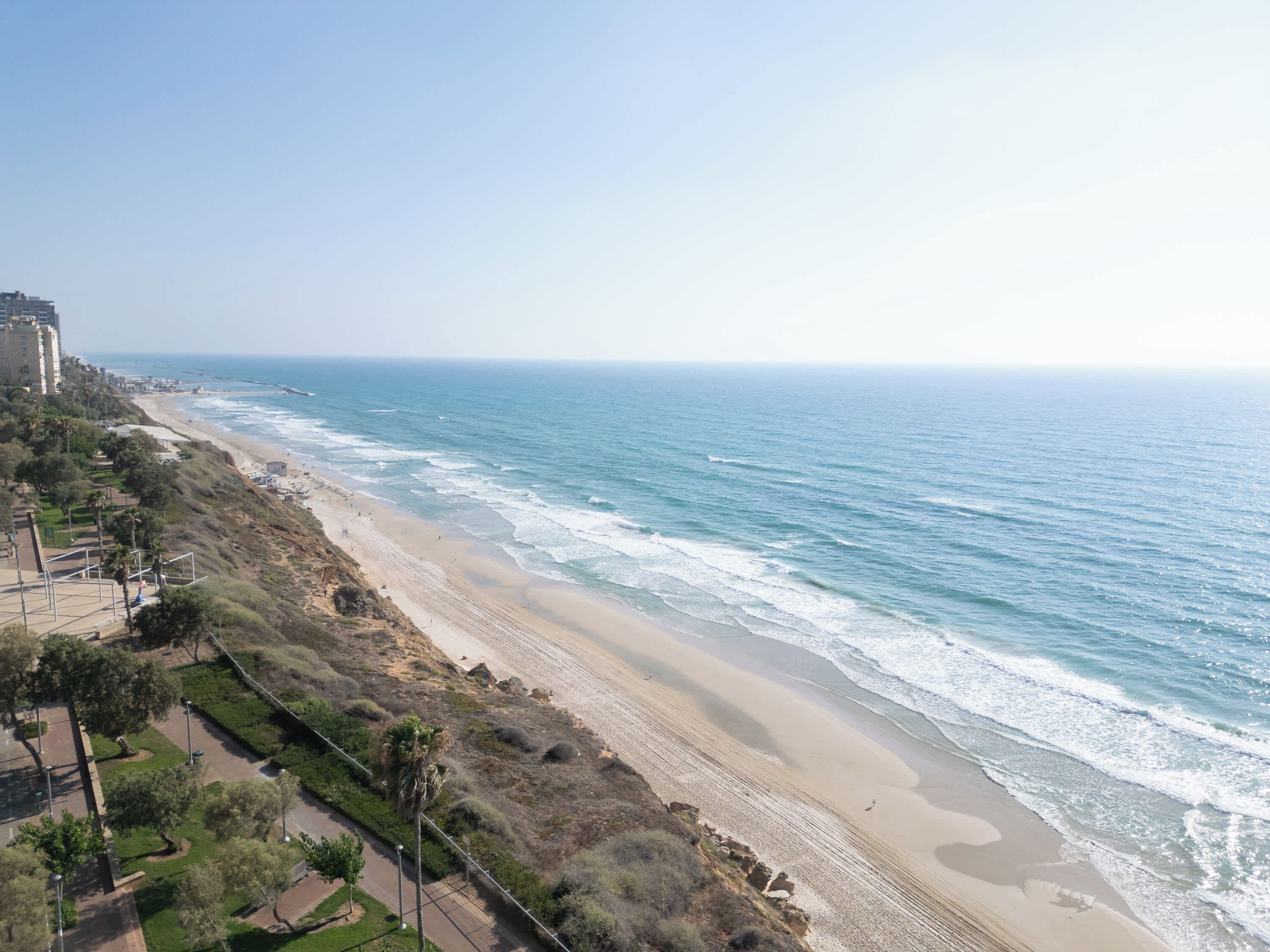 Vista costera con playa, océano y un edificio al fondo.