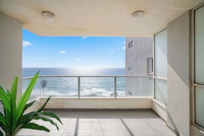 A balcony with a view of the ocean, a potted plant, and a tiled floor. - Stunning Sea View 3BDR With Terrace By Isrentals (Netanya)