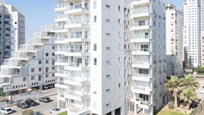 En flervåningsbyggnad med bostäder, balkonger, en parkeringsplats och en välskött gräsmatta.