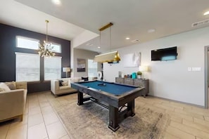 A modern living room with a pool table, a sofa, and a television.