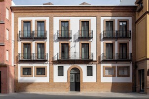 A multi-story building with a symmetrical facade, multiple balconies, and a central entrance with an archway.