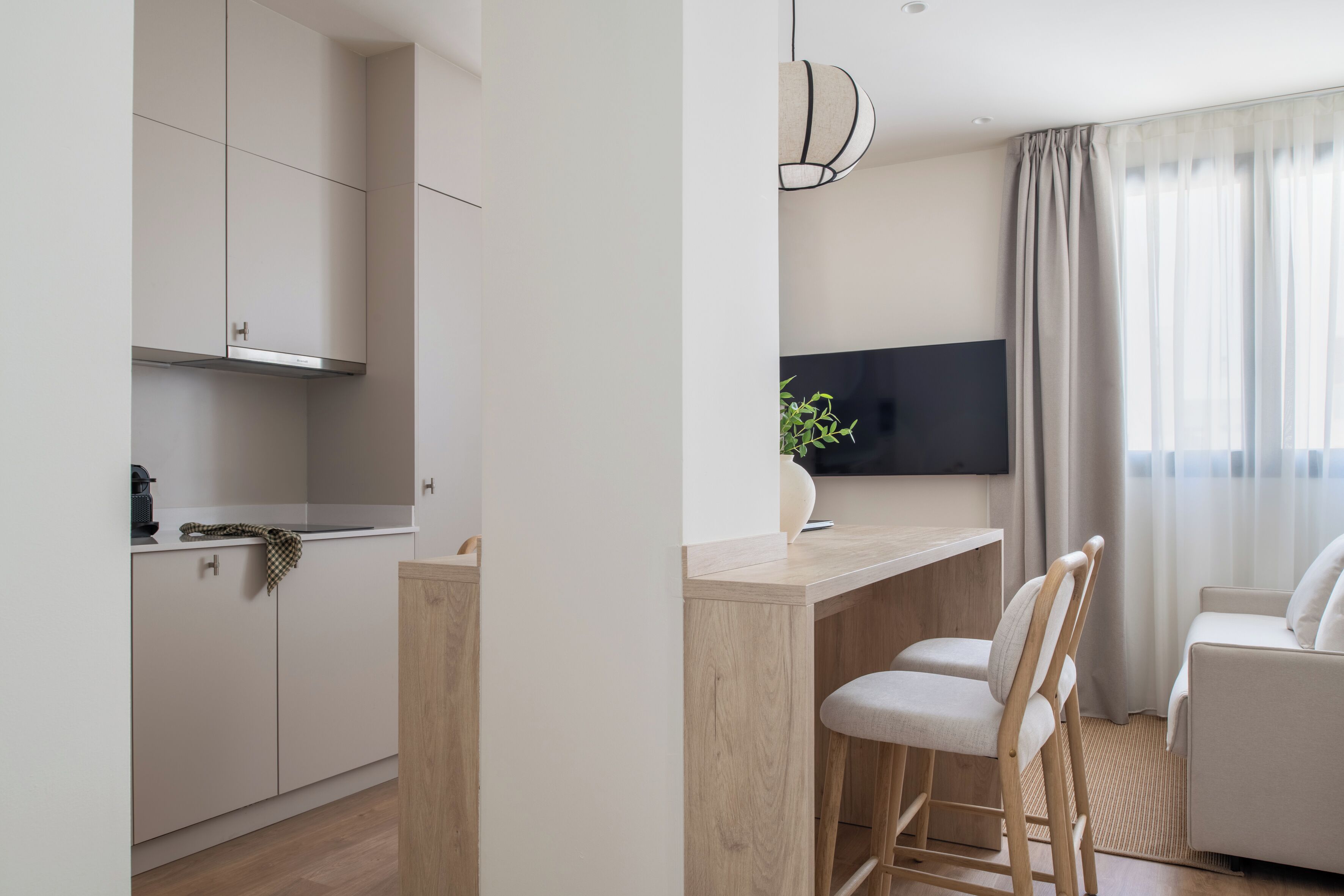 Una cocina moderna con armarios blancos, encimera de madera y un rincón comedor con dos sillas.