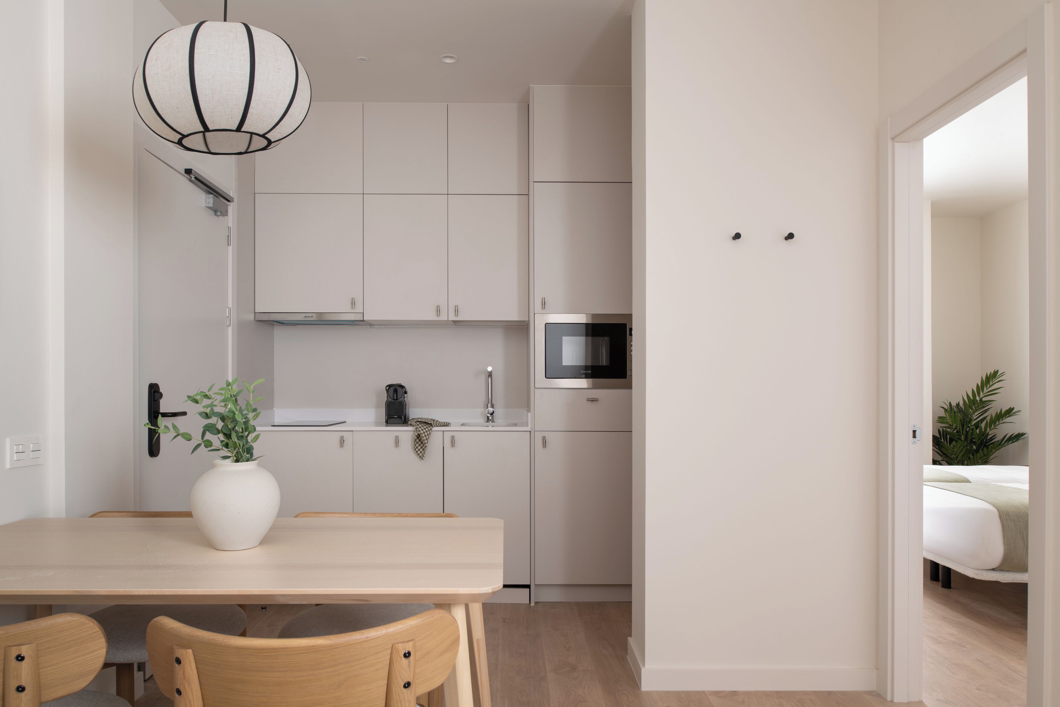 A modern kitchen with white cabinets, a microwave, and a dining area with a table and chairs.