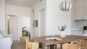 A modern living room with a dining table, chairs, a sofa, a TV, and a kitchen area. - Líbere Seville Triana (Seville)