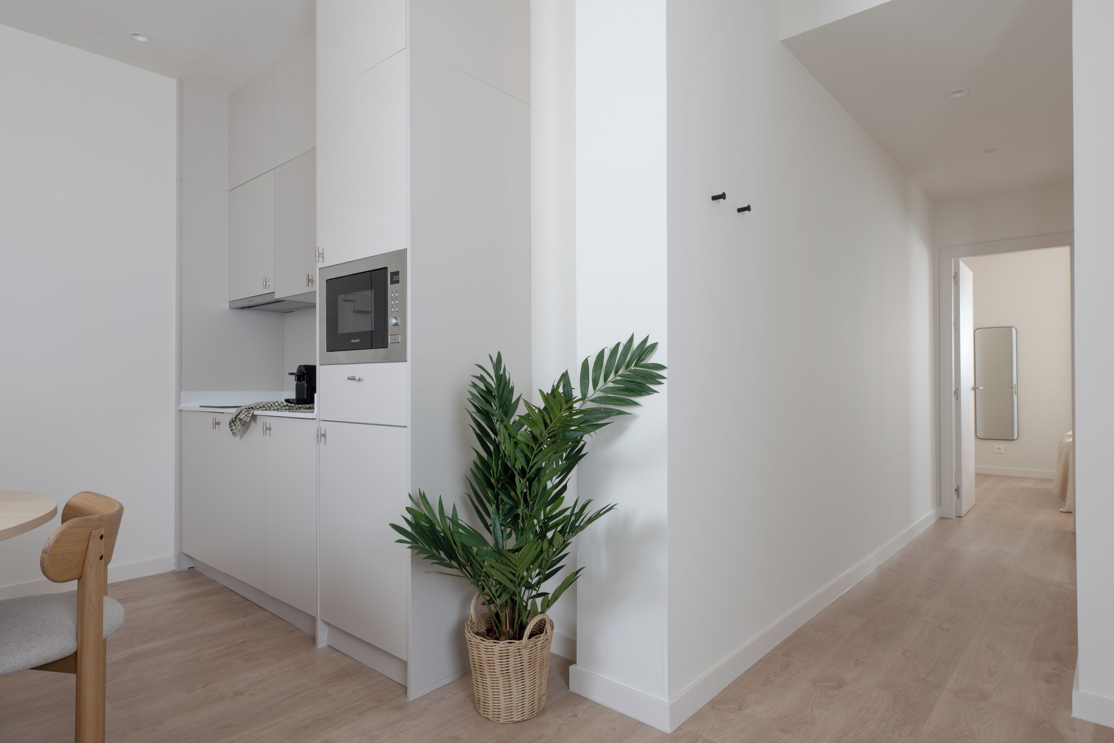 Una cocina moderna con armarios blancos, un microondas y una planta en maceta.