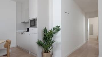 Una cocina moderna con armarios blancos, un microondas y una planta en maceta.