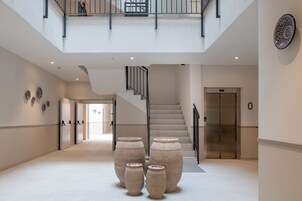 A spacious lobby with a staircase, large vases, and a modern elevator.