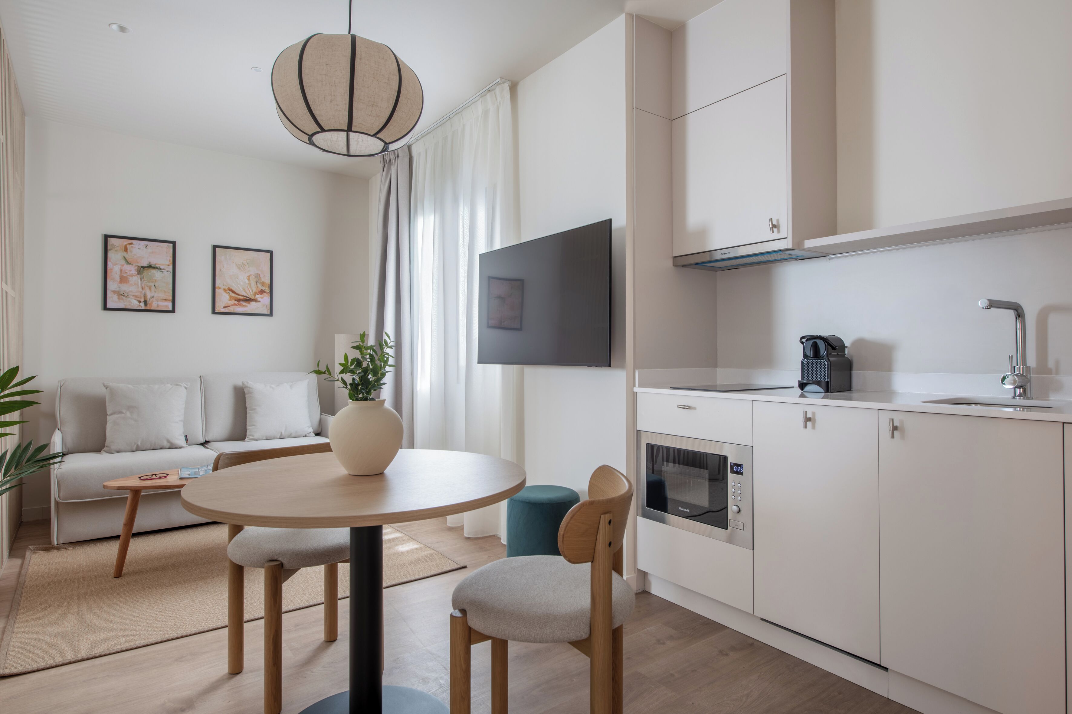 Una sala moderna con sofá, una mesa de comedor y una zona de cocina con armarios y electrodomésticos.