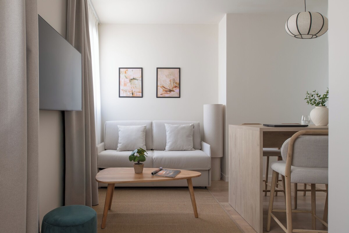 A modern living room with a sofa, a coffee table, and a dining area with a chair.