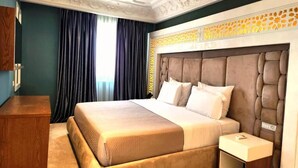Habitación de hotel con una cama grande, una mesita de noche, un aparador de madera y un techo decorativo.