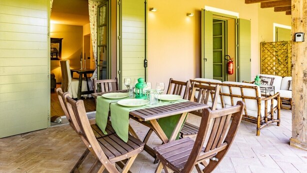 A dining area with a wooden table and chairs, a green tablecloth, and a fire extinguisher in the background. - Lagotto House - Garden and Parking in the Langhe (Novello)