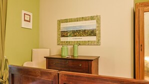 A room with a bed, a wooden dresser, a framed picture on the wall, and a green wall.