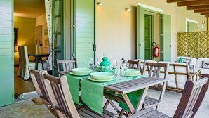 A dining area with a table set for four, green tablecloths, and wooden chairs.