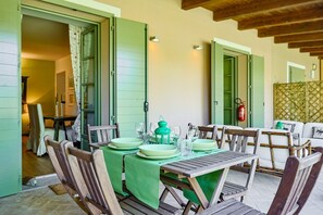 A dining area with a table set for four, green tablecloths, and wooden chairs.