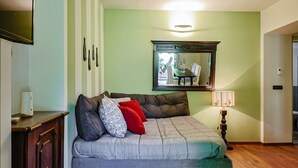 A room with a sofa, a mirror, a lamp, and a door.
