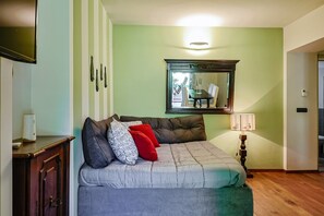 Una habitación con sofá, espejo, lámpara y puerta.