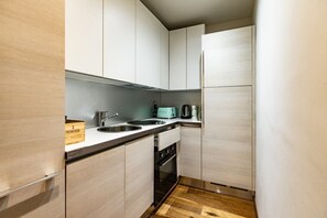 A compact kitchen with a sink, a toaster, and a refrigerator.