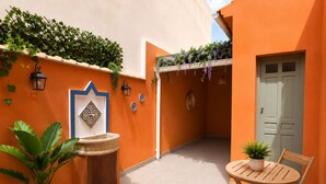 A courtyard with a fountain, potted plants, a table with chairs, and a door. - Adela House (Maracena)