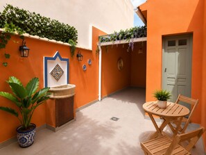 A courtyard with a fountain, potted plants, a table with chairs, and a door. - Adela House (Maracena)